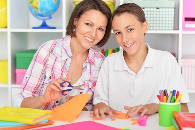 Mère et fils collant et coupant du papier coloré