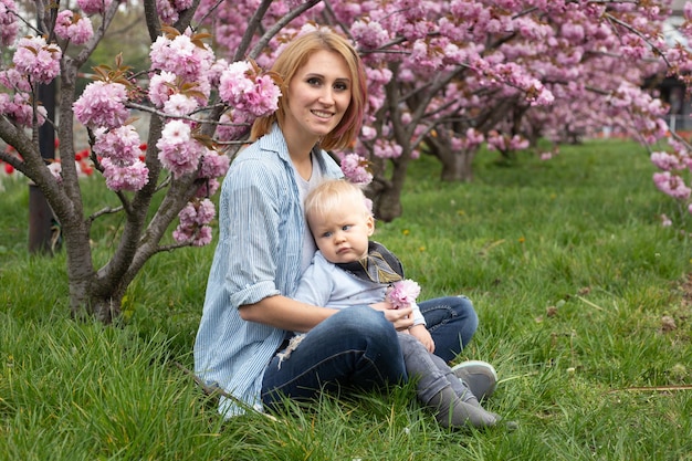 Mère et fils dans la nature jouant au parc de printemps Petit garçon et mère s'amusent le week-end dans les jardins fleuris de Sakura