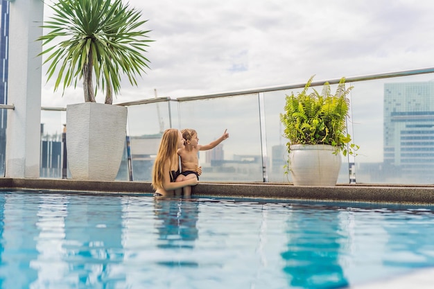 Mère et fils dans la piscine parmi les gratte-ciel et la grande ville se détendent dans la grande ville se reposent de