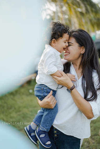 Mère avec fils enfant jouant s'amusant ensemble sur l'herbe en journée d'été ensoleillée.