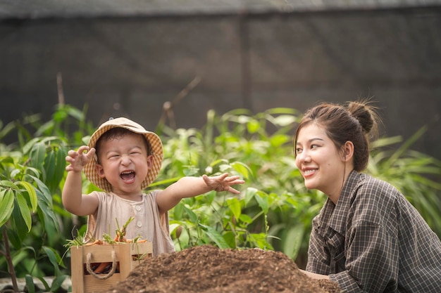 Photo mère et fils enfant plantant des légumes dans le jardin de la maison