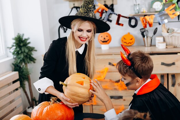 Photo la mère et le fils envisagent la citrouille et passent des moments amusants à la maison. halloween