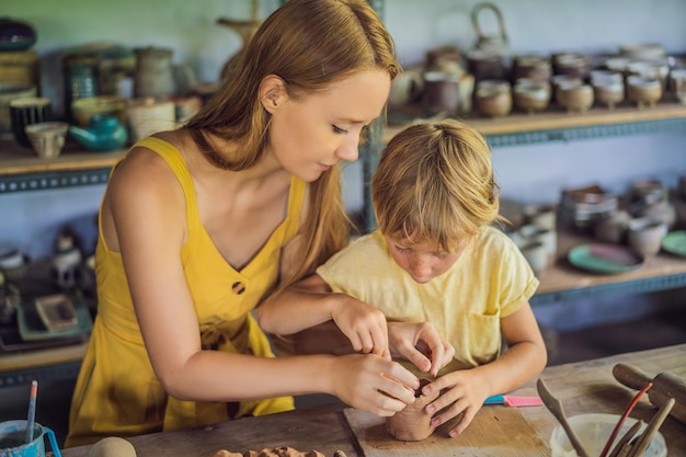 Mère et fils faisant un pot en céramique dans un atelier de poterie