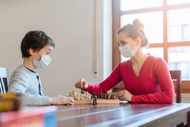 Mère et fils jouant aux échecs pour tuer un certain temps pendant le couvre-feu dans les crises