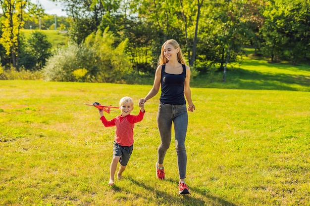 Mère et fils jouant avec un grand modèle d'avion jouet dans le parc.