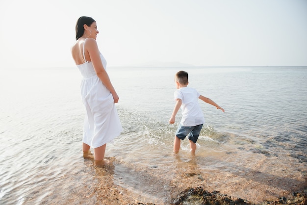 Mère et fils jouant sur la plage pendant la journée. Concept de famille sympathique.