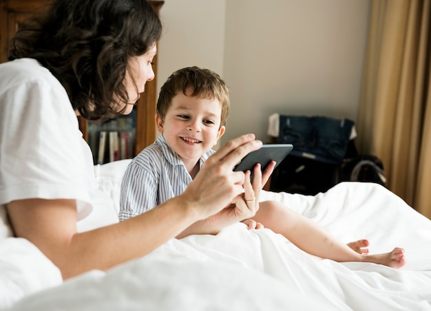 Mère et fils jouant sur smartphone au lit