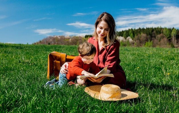 Mère et fils avec un livre assis sur le pré.