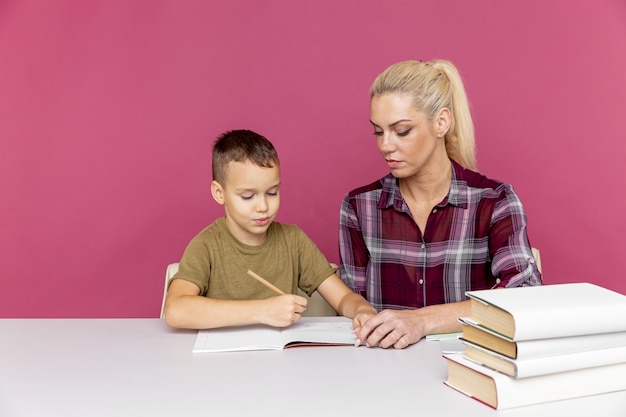 Mère avec fils à la maison à faire leurs devoirs ensemble en période de quarantaine.