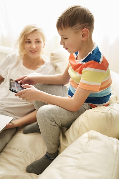 Mère et fils à la maison. Le garçon apprend à utiliser une tablette PC.