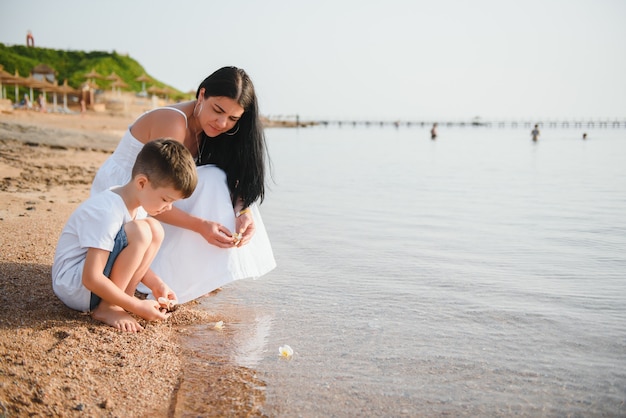 Mère et fils marchant sur la plage au coucher du soleil