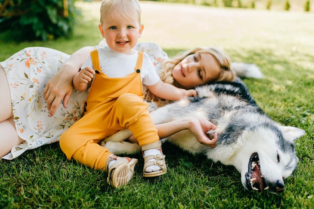 Mère et fils posant avec un chien sur l'herbe