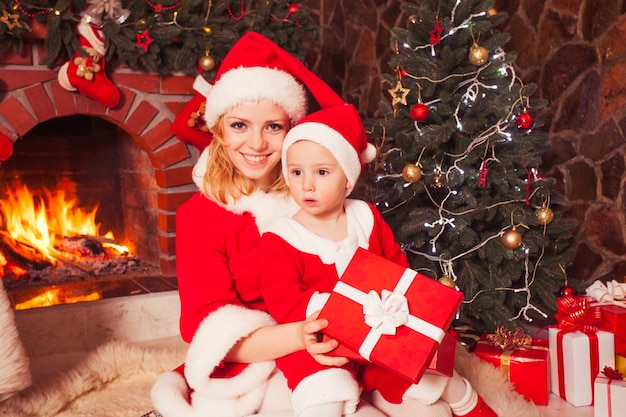 La mère et le fils sont assis près de la cheminée et du sapin de Noël. Regard de famille dans une boîte-cadeau.