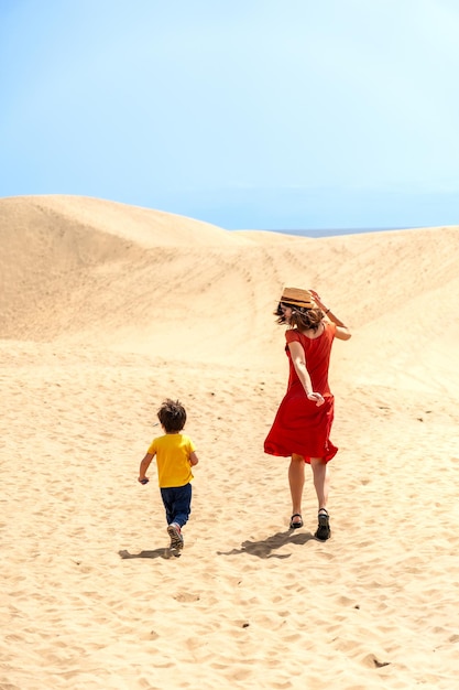 Mère et fils touristes qui s'amusent à courir dans les dunes de Maspalomas Gran Canaria îles Canaries