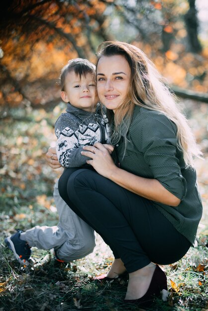 Photo mère avec fils trois ans en automne la forêt, étreinte et tendresse