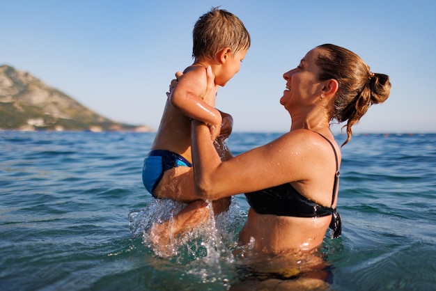 La mère gaie joue avec son fils en mer