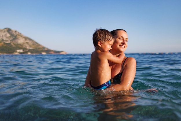 La mère gaie joue avec son fils en mer