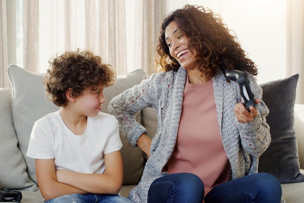 Photo mère garçon et contrôleur sur le canapé pour jouer avec un concours de perdants et un concours avec rire dans la maison maman jeune fils et jeux en ligne sur le canapé du salon avec le visage bouleversé pour la perte dans la maison familiale