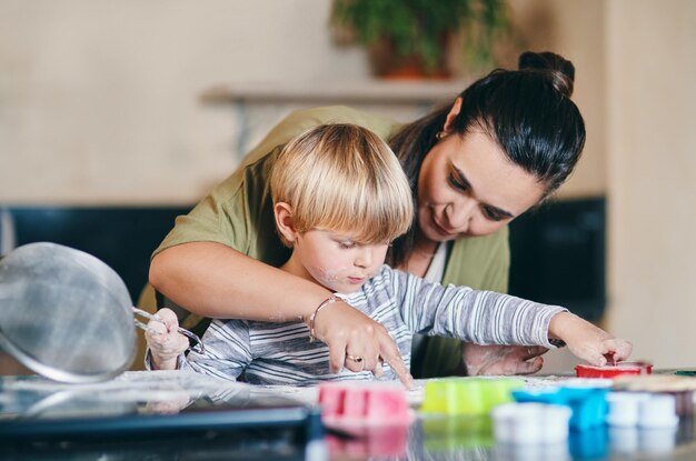 Photo mère garçon enfant et enseignant la cuisson dans la cuisine pour apprendre les compétences domestiques ou les biscuits dans la maison familiale cuisiner maman et fils dans la maison pour l'éducation des biscuits ou de la nourriture avec amour, soin ou développement