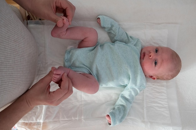 Photo une mère habille son nouveau-né à la maison. tester le réflexe des doigts sur les jambes.