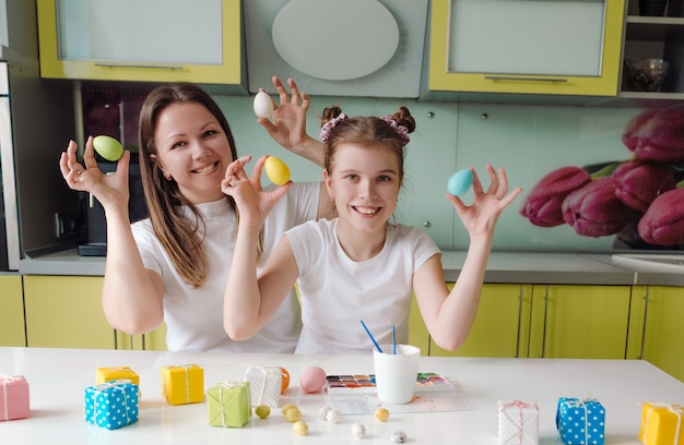 Une mère heureuse avec sa belle fille souriante tient des oeufs de Pâques colorés dans ses mains. préparatifs pour les vacances de Pâques