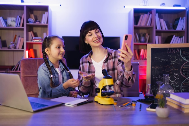 Une mère heureuse avec sa fille essayant d'examiner les cellules végétales au microscope