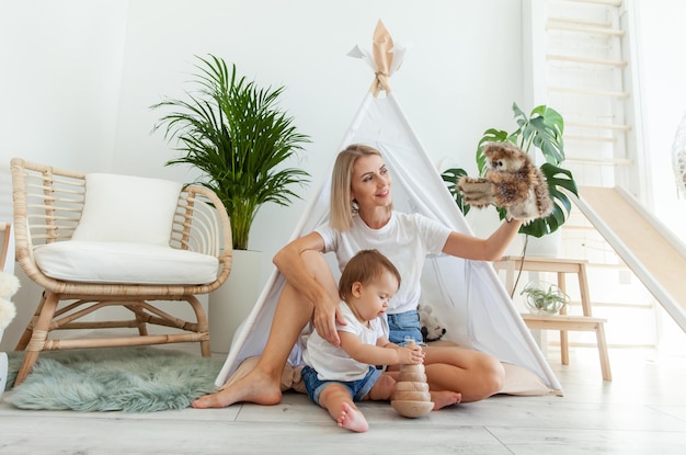 Une mère heureuse et sa petite fille jouent au wigwam à la maison.