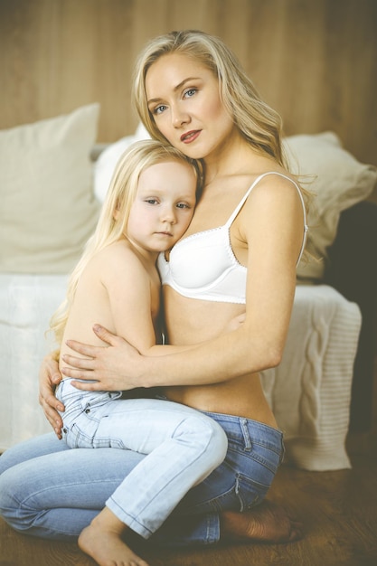 Photo une mère heureuse et sa petite fille se câlinent pendant qu'elles s'habillent.