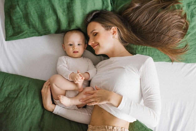 Une mère heureuse et satisfaite se repose sur le lit avec son bébé