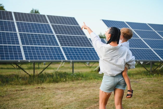 Une mère heureuse et son petit fils marchent près des panneaux solaires Le concept d'énergie verte