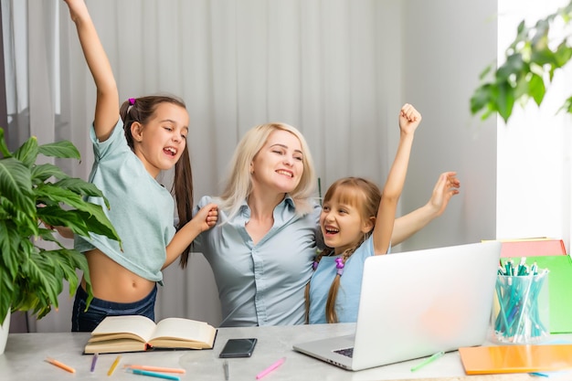 une mère heureuse travaille sur un ordinateur portable et deux petites filles jouent