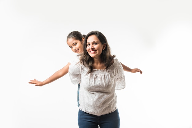 Mère indienne fille sur fond blanc étreindre, embrasser, monter, voler, pointer, présenter sur fond blanc