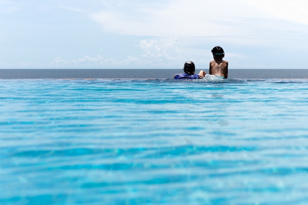 Mère et jeune fils se détendent dans la piscine donnant sur l'océan en vacances d'été.