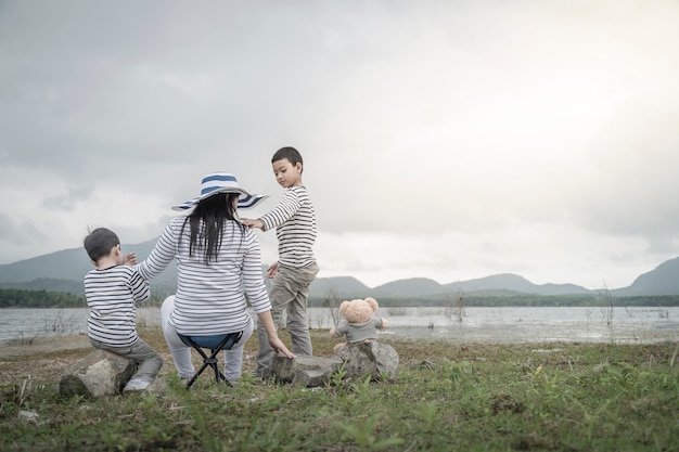 Mère avec de jeunes filles et fils en pique-nique près du lac.