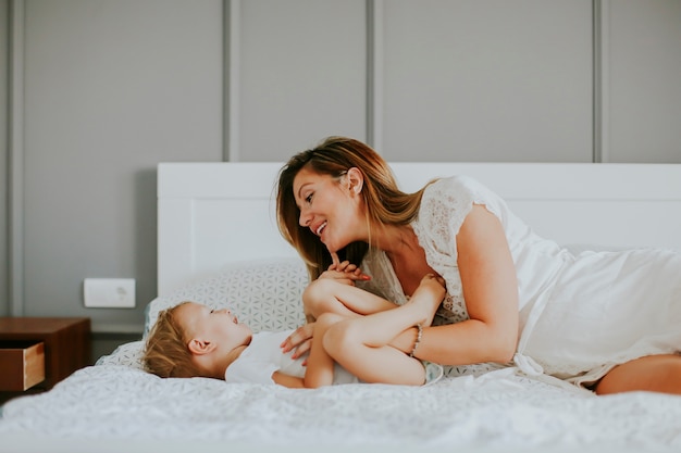 Mère jouant avec le petit garçon sur le lit dans la chambre