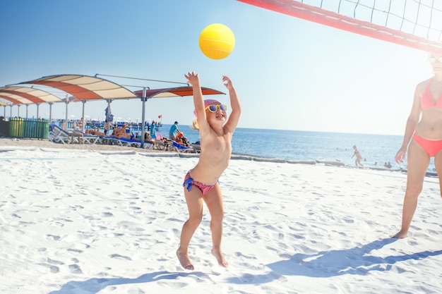 Mère jouant avec sa petite fille mignonne à la plage