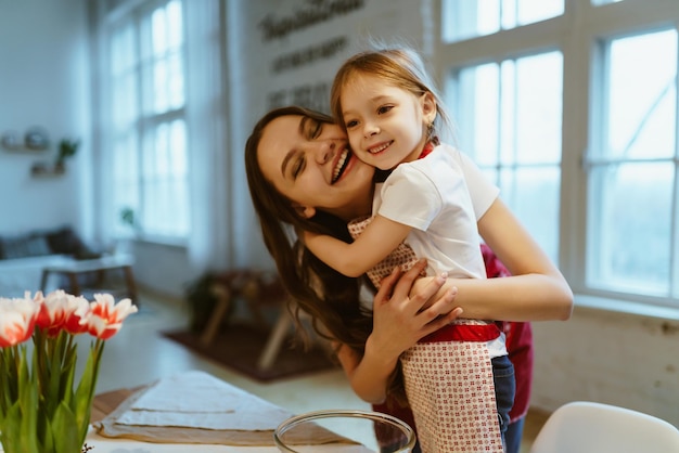 Une mère joyeuse dans la cuisine embrasse sa fille