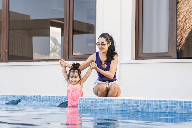 Mère latino-américaine profitant des vacances d'été dans une piscine avec sa fille