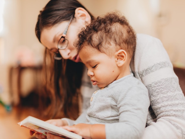 Mère lisant un livre assise avec son fils à la maison