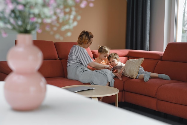 Mère lisant un livre avec deux enfants sur un canapé
