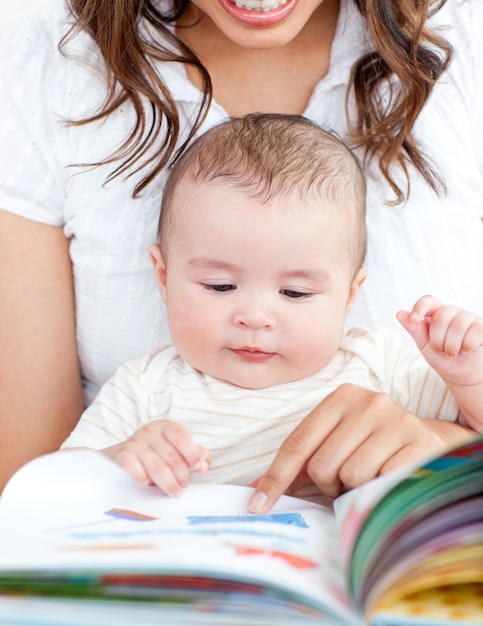 Mère lumineuse montrant des images dans un livre à son petit fils mignon