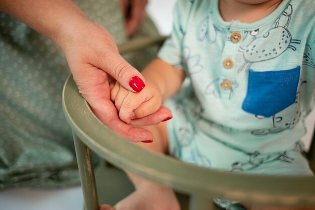 Une mère avec une manucure rouge tient la petite main de son fils