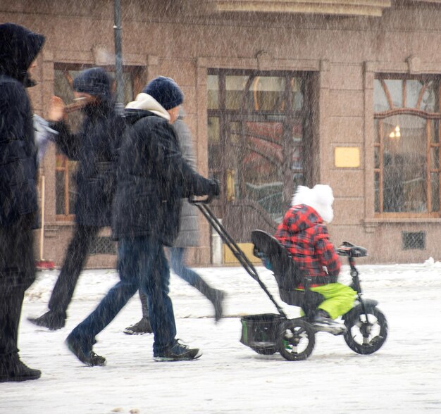 Mère marchant avec l'enfant en petit vélo en journée d'hiver enneigée. Flou de mouvement intentionnel. Image défocalisée