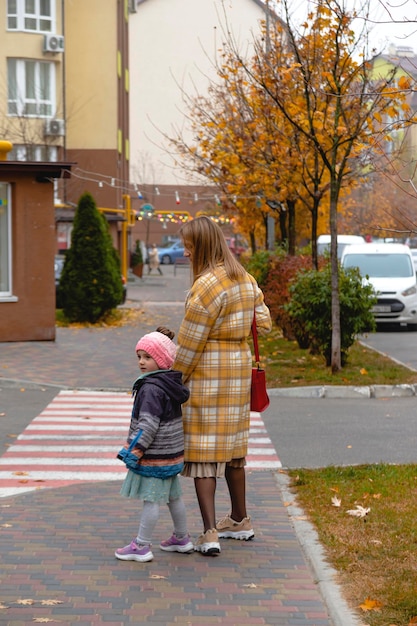 Mère marchant avec sa fille sur les couleurs d'automne de la rue d'automne