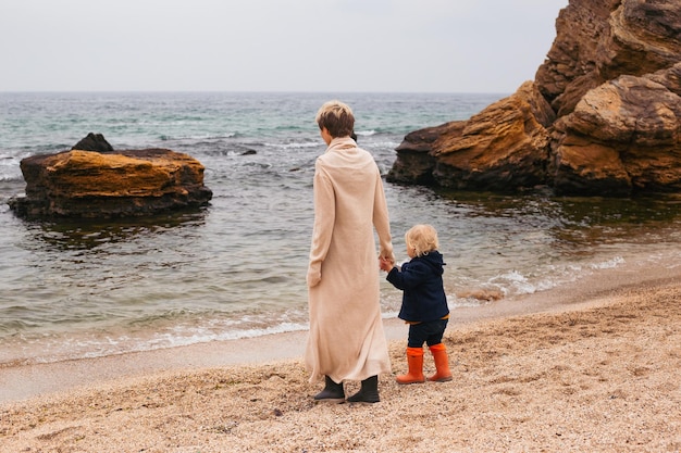 Mère marchant avec son fils par une journée ensoleillée près de la mer Repos sur la plage Une famille heureuse