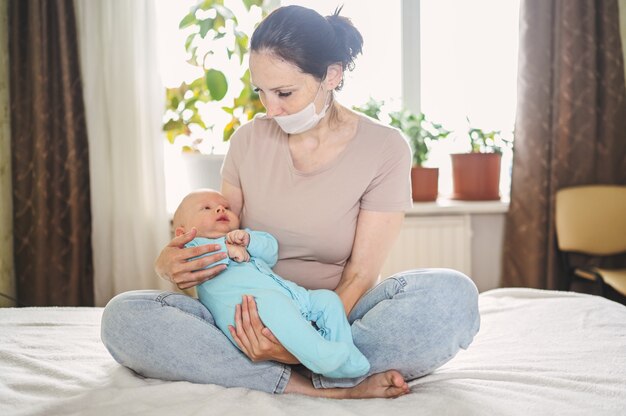 Mère en masque de protection tenant son fils nouveau-né