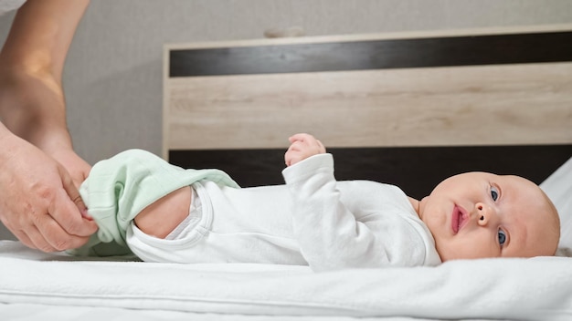 Mère met des collants verts sur une adorable petite fille à la maison