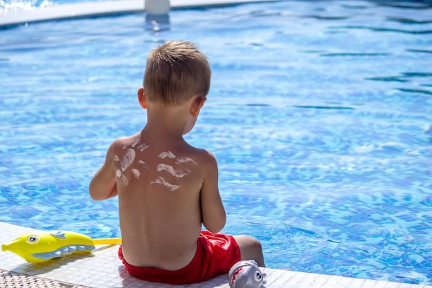 Mère met de la crème sur le dos de son fils Prendre soin de la peau de bébé Écrans solaires en voyage