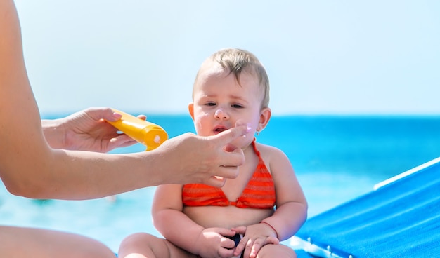 Mère mettant de la crème solaire sur un bébé