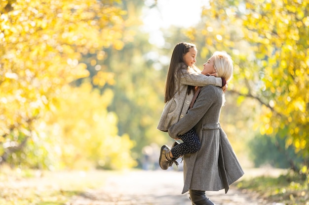 Mère à la mode avec sa fille. Famille dans un parc d'automne. Petite fille dans un manteau.